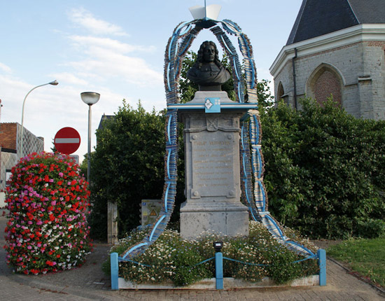 Het knappe standbeeld nabij de kerk. Aan de zijkant staat ten lezen over het monument: 'Met bestuurs- en volksgiften door den Oudheidkundigen Kring van het Land van Waes opgerigt en ingehuldigd. 1862.'